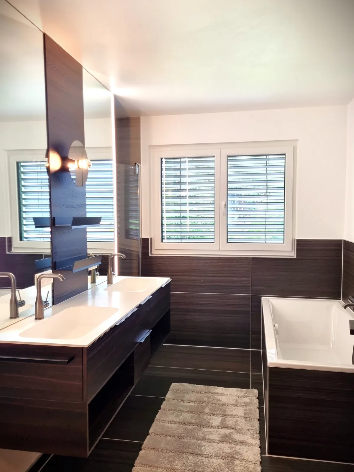 Badezimmer mit Doppelwaschtisch, Badewanne und dunklen Wandfliesen – Badsanierung, Kärnten
